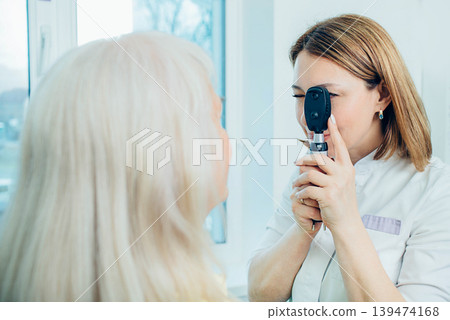Doctor Optometrist examining old man's eyes with special eye equipment Doctor Optometrist examining old man's eyes with special eye equipment 139474168