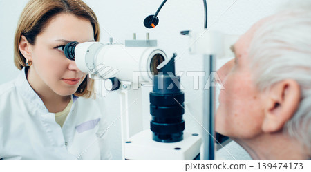 Doctor Optometrist examining old man's eyes with special eye equipment Doctor Optometrist examining old man's eyes with special eye equipment 139474173
