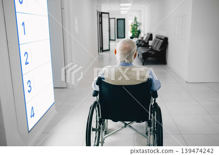 Lonely senior man in wheelchair sitting at the hospital corridor, back view. Lonely senior man in wheelchair sitting at the hospital corridor, back view. 139474242