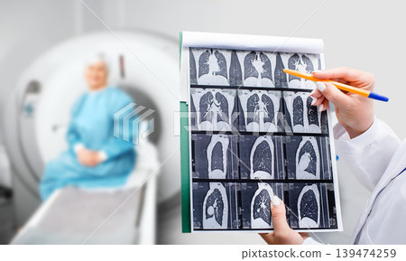 A healthcare worker examines CT scan images while seated patient awaits results in a medical clinic setting A healthcare worker examines CT scan images while seated patient awaits results in a medical clinic setting 139474259