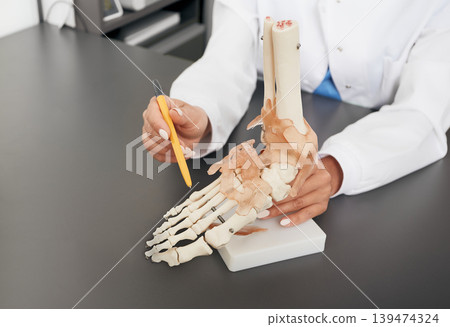Doctor orthopedist shows to the anatomical model of the foot. Arthritis, foot injuries, flat feet and pain Doctor orthopedist shows to the anatomical model of the foot. Arthritis, foot injuries, flat feet and pain 139474324