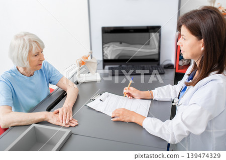 Senior woman tells osteopathic doctor about joint pain and hand tremor. Diagnostics and treatment joint pain in elderly people Senior woman tells osteopathic doctor about joint pain and hand tremor. Diagnostics and treatment joint pain in elderly people 139474329