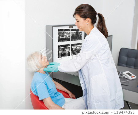 Doctor checking the thyroid gland of an elderly woman. Diagnosis of thyroid diseases. Endocrine system treatment 139474353