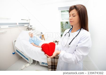 Care for an elderly patient in a hospital. Doctor holding a heart model. Cardiology, medical care for patients with heart disease. Heart attack, treatment, and recovery Care for an elderly patient in a hospital. Doctor holding a heart model. Cardiology, medical care for patients with heart disease. Heart attack, treatment, and recovery 139474382