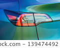 Close-up of modern car rear tail light, metallic turquoise vehicle body, glossy reflective surfaces, red clear LED lamp sections. Striking colors, smooth curves, aesthetics, technology, innovative car 139474492