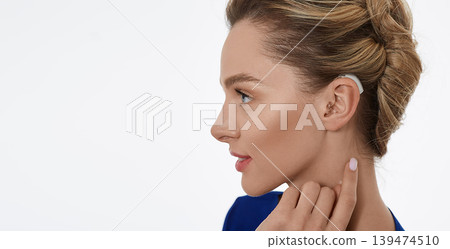 Portrait of woman with hearing aid behind the ear for treatment deafness, side view. Hearing aids, hearing solutions Portrait of woman with hearing aid behind the ear for treatment deafness, side view. Hearing aids, hearing solutions 139474510