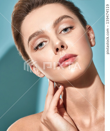 Beauty woman with fresh, moisturized facial skin and natural plump lips over blue background. Skin care concept 139474519