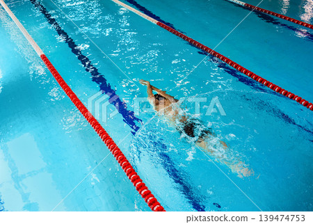 Swimmer dives underwater at blue swimming pool, top view. Swimmer dives underwater at blue swimming pool, top view. 139474753