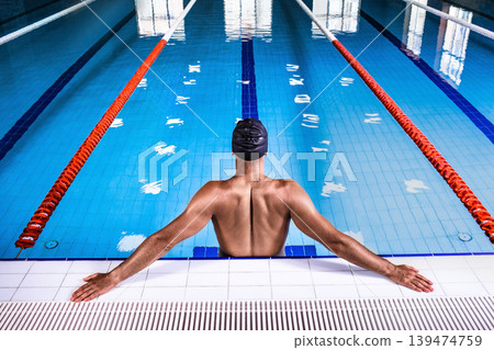 A swimmer wearing a swimming cap stands in the pool, back view. An athlete prepares to swim the fastest this swim. A swimmer wearing a swimming cap stands in the pool, back view. An athlete prepares to swim the fastest this swim. 139474759