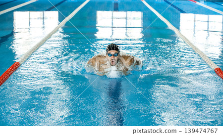 Swimming in motion. Swimmer demonstrates the butterfly stroke technique. Training different swimming styles. Soft focus in motion Swimming in motion. Swimmer demonstrates the butterfly stroke technique. Training different swimming styles. Soft focus in motion 139474767
