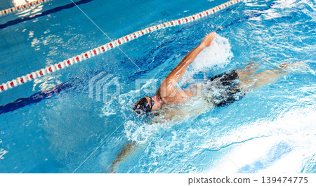 Man swimmer is swimming in the pool, backstroke technique swimming. Shot of swim in motion Man swimmer is swimming in the pool, backstroke technique swimming. Shot of swim in motion 139474775