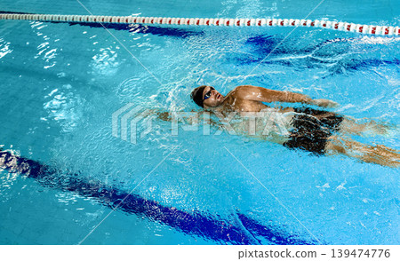 Man swimmer is swimming in the pool, backstroke technique swimming. Shot of swim in motion, top view 139474776