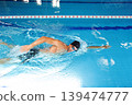 Man swimmer is swimming in the pool. Freestyle stroke, front crawl stroke. Swimming in blue pool, side view. breathing technique during swimming 139474777