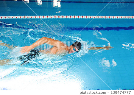Man swimmer is swimming in the pool. Freestyle stroke, front crawl stroke. Swimming in blue pool, side view. breathing technique during swimming Man swimmer is swimming in the pool. Freestyle stroke, front crawl stroke. Swimming in blue pool, side view. breathing technique during swimming 139474777