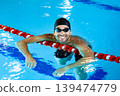 Portrait of a positive professional swimmer in a pool resting after swimming in the pool. Swimming training 139474779