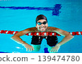 Portrait of a positive professional swimmer in a pool resting after swimming in the pool. Swimming training 139474780