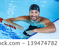 Portrait of a positive professional swimmer in a pool resting after swimming in the pool. Swimming training 139474782