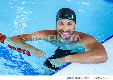 Portrait of a positive professional swimmer in a pool resting after swimming in the pool. Swimming training 139474782