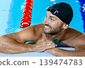 Smiling swimmer looking away, relaxing on the rooftop pool. Swimmer in the swimming pool,headshot 139474783
