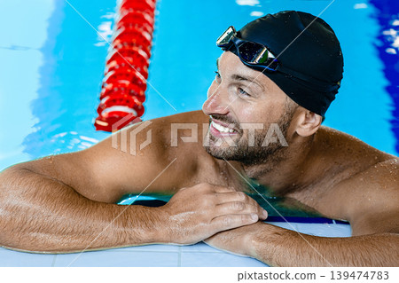 Smiling swimmer looking away, relaxing on the rooftop pool. Swimmer in the swimming pool,headshot Smiling swimmer looking away, relaxing on the rooftop pool. Swimmer in the swimming pool,headshot 139474783