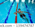 Portrait of a positive professional swimmer in a pool resting after swimming in the pool. Swimming training 139474787
