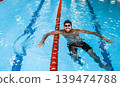 Portrait of a positive professional swimmer in a pool resting after swimming in the pool. Swimming training 139474788