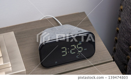 Smart clock displaying time and temperature on a bedside table with a modern design, featuring a fabric texture and sleek digital interface Smart clock displaying time and temperature on a bedside table with a modern design, featuring a fabric texture and sleek digital interface 139474803