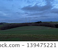 Modern wind turbines across rolling countryside fields under dramatic cloudy evening sky. Sustainable energy concept with renewable power generation in natural landscape 139475221