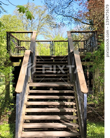 A wooden staircase with metal railings leading to an observation deck in a spring park. A wooden staircase with metal railings leading to an observation deck in a spring park. 139475679