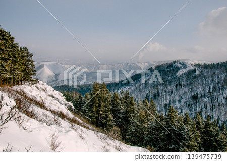 Landscape of snowy Siberia Krasnoyarsk mountains, peaks range in haze winter 139475739