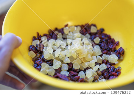 A close-up shot of a bright yellow bowl filled with a mixture of dried cranbe A close-up shot of a bright yellow bowl filled with a mixture of dried cranbe 139476232