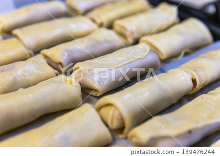 Top View of Many Uncooked Crepe Rolls with Meat Filling on a Tray 139476244