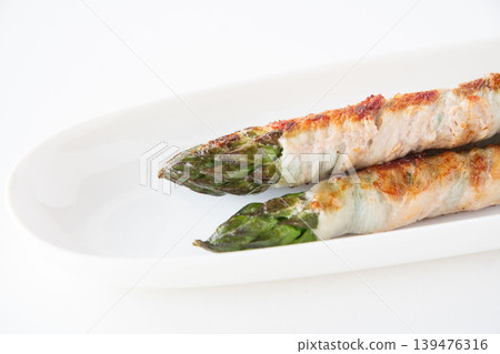 Asparagus wrapped in meat on a white plate Asparagus wrapped in meat on a white plate 139476316