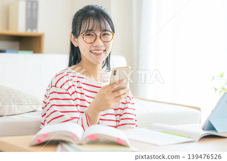 年輕女子邊看智慧型手機邊學習 139476526