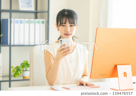 A young woman operating a smartphone in the office A young woman operating a smartphone in the office 139476557