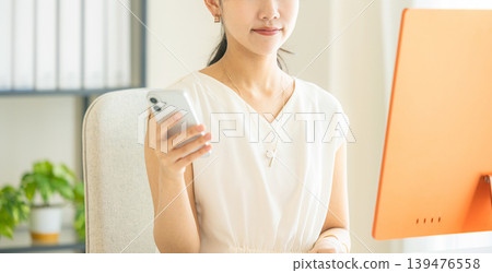 A young woman operating a smartphone in the office A young woman operating a smartphone in the office 139476558
