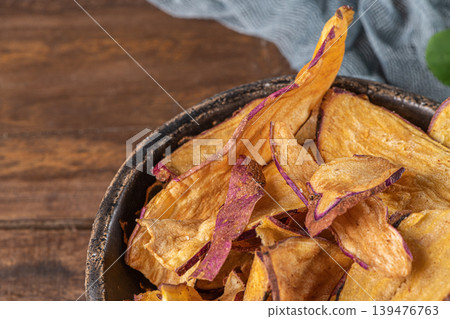 Delicious sweet potato chips in bowl, on table. 139476763