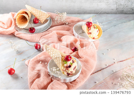 Traditional waffle cones with ice cream and cherry fruits on marble stone surface 139476793
