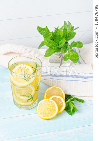 Preparation of the lemonade drink. Lemonade in the jug and lemons with rosemary on the table outdoor. Preparation of the lemonade drink. Lemonade in the jug and lemons with rosemary on the table outdoor. 139476798