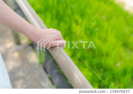 A woman's hand grasping a handrail 139476837