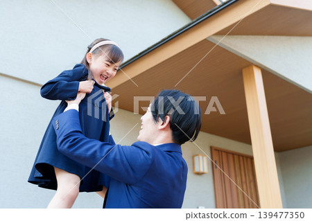 一位父親在家門前抱起了女兒。 139477350