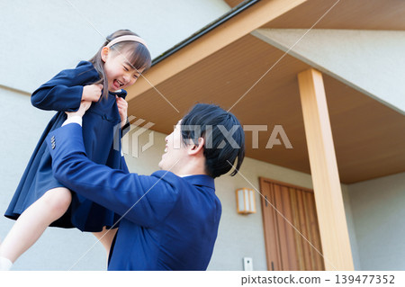 一位父親在家門前抱起了女兒。 139477352