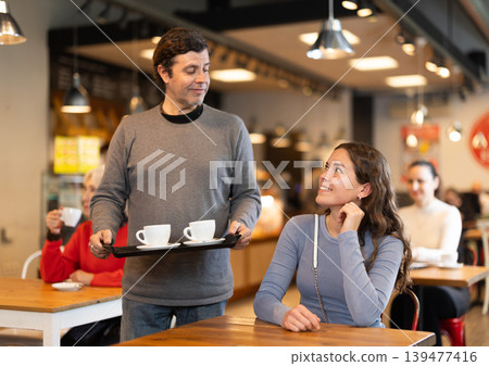 Man came to girlfriend with coffee on tray, meeting relatives in food court Man came to girlfriend with coffee on tray, meeting relatives in food court 139477416