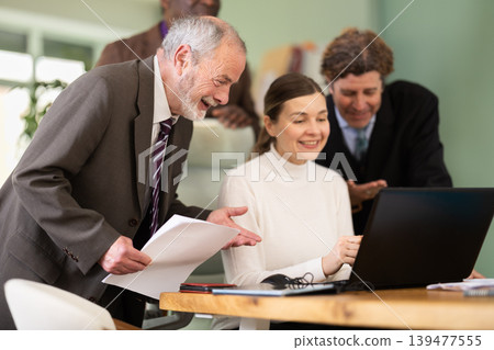 Team of businessmen laugh at funny video posted online during coffee break Team of businessmen laugh at funny video posted online during coffee break 139477555