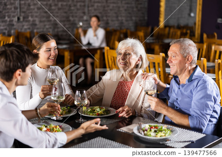 Happy senior couple meeting with adult children in restaurant Happy senior couple meeting with adult children in restaurant 139477566
