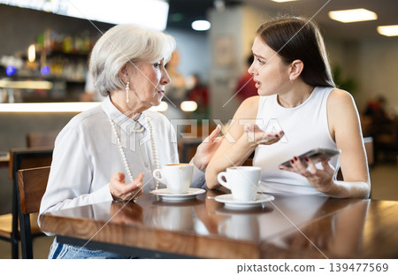 Elderly woman comforts young woman in cafe Elderly woman comforts young woman in cafe 139477569