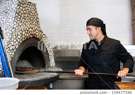 Skilled man chef preparing pizza in restaurant 139477596