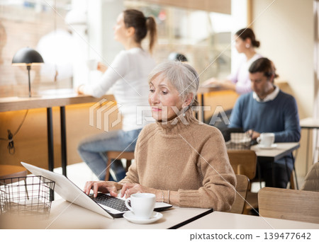 Confident senior female cafe customer enjoying peace and quiet while working on laptop 139477642