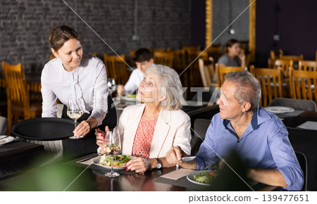 Female hostess serves puts on table order for elderly spouses 139477651