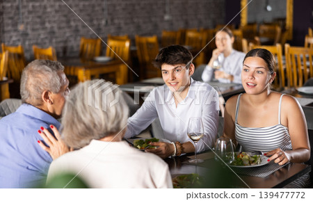 Elderly couple and young couple having dinner in restaurant Elderly couple and young couple having dinner in restaurant 139477772
